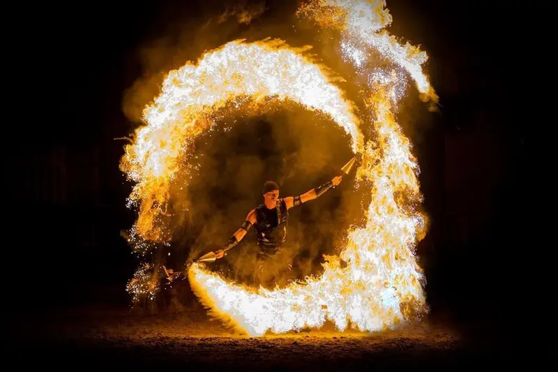 Fire performer spinning a ring of flames at a night event