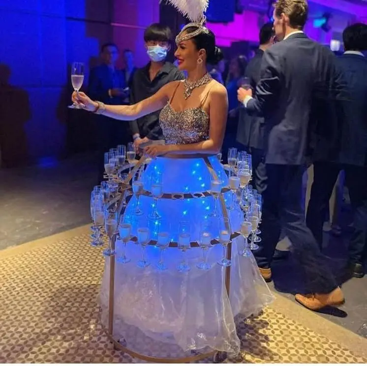 Roving performer in a light-up champagne skirt serving glasses of champagne to guests at an evening reception